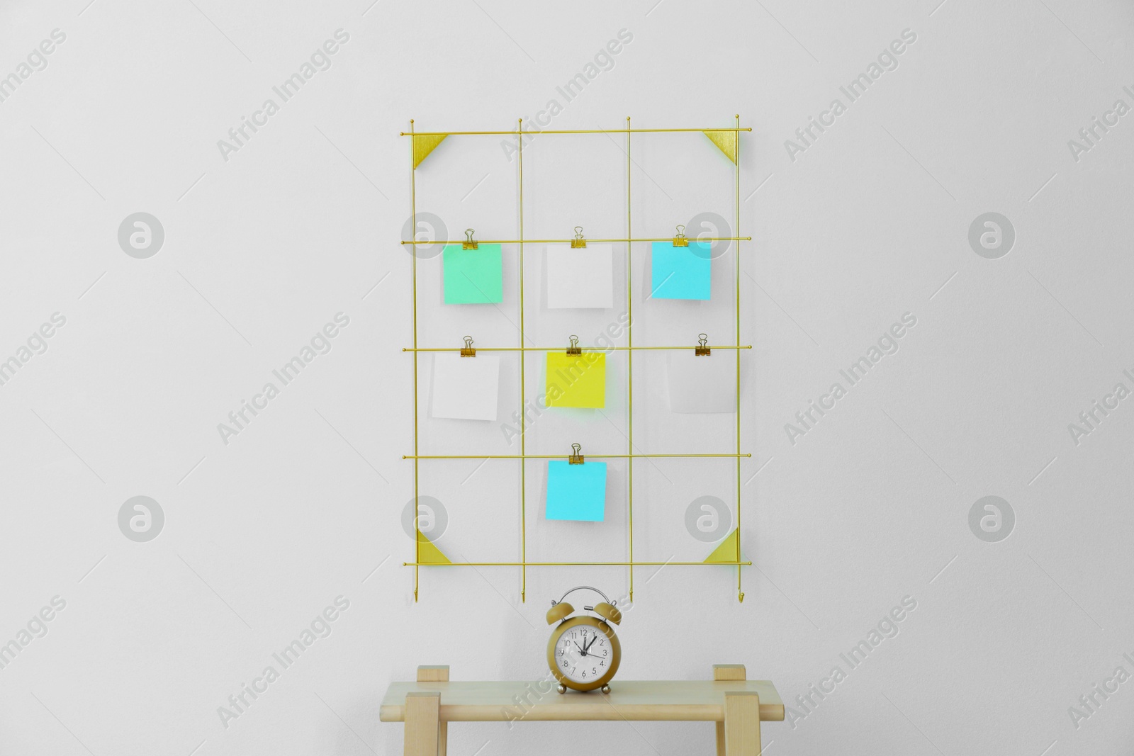 Photo of Mood board with blank paper notes and alarm clock on wooden ladder near white wall