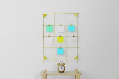 Photo of Mood board with blank paper notes and alarm clock on wooden ladder near white wall