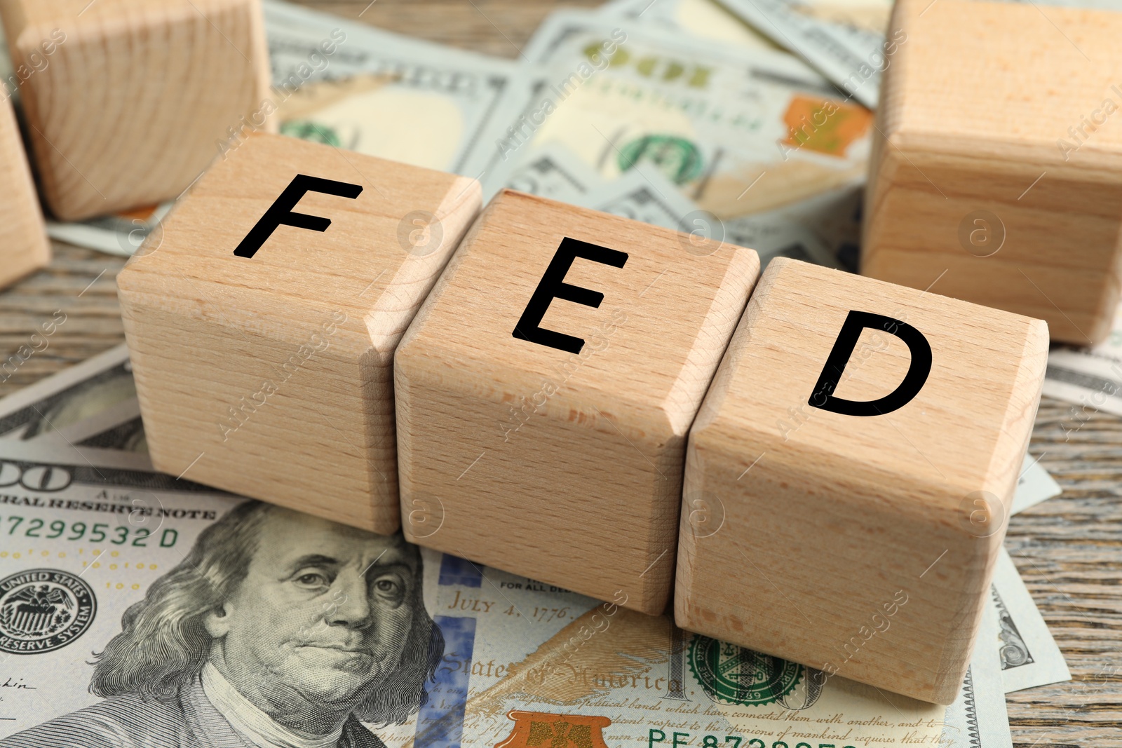 Photo of Wooden cubes with letters Fed (Federal Reserve System) and dollar banknotes on table, closeup