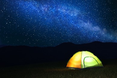 Photo of Modern camping tent in wilderness at night, space for text