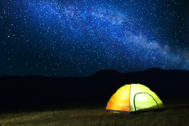 Photo of Modern camping tent in wilderness at night, space for text