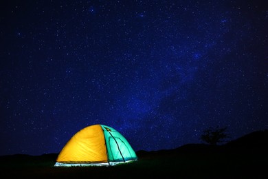 Photo of Modern camping tent in wilderness at night