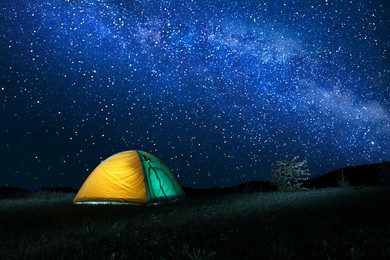 Photo of Modern camping tent in wilderness at night