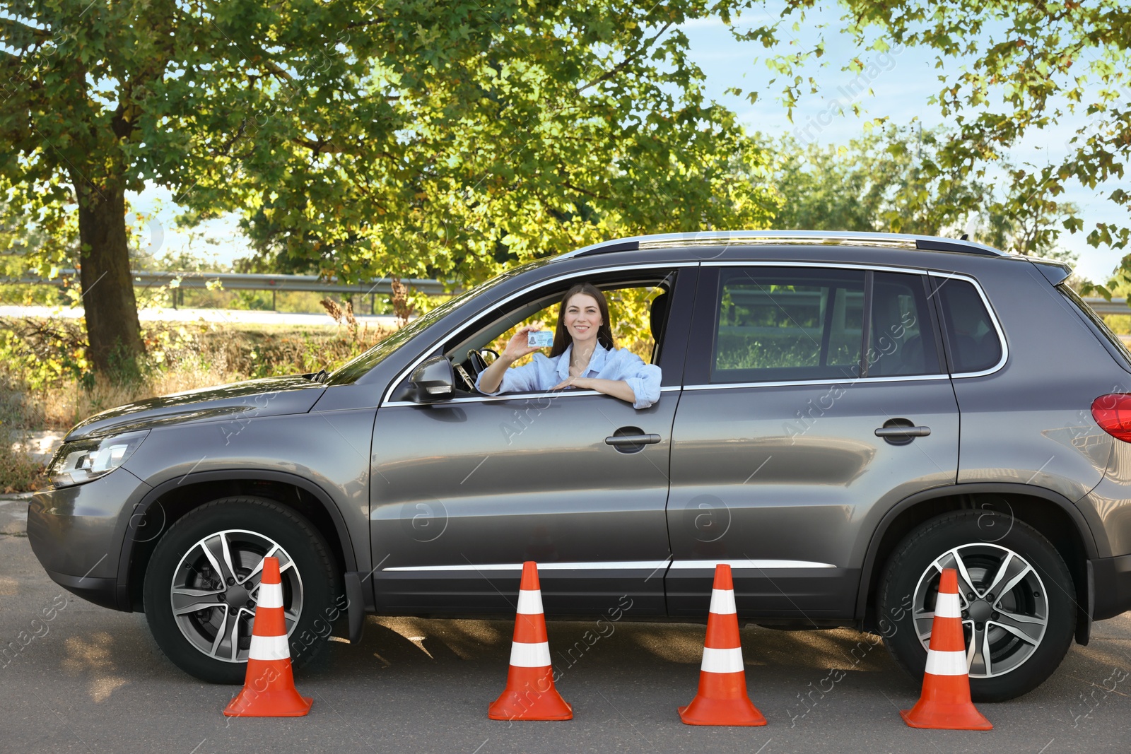 Photo of Driving school. Woman with driving license in car after exam