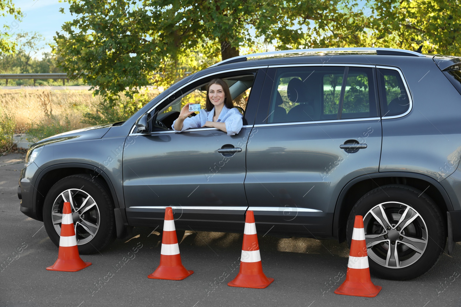 Photo of Driving school. Woman with driving license in car after exam