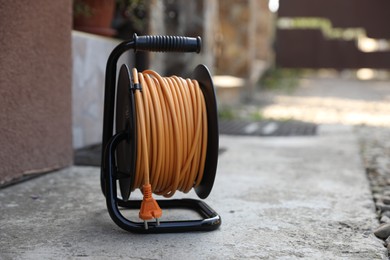 Photo of Extension cord reel on asphalt outdoors, space for text