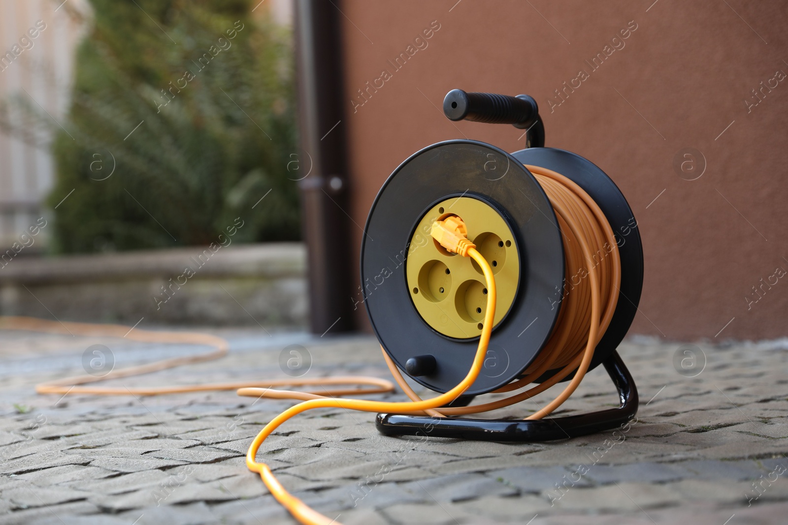 Photo of Extension cord reel on paved pathway outdoors, space for text