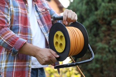 Photo of Man with extension cord reel outdoors, closeup