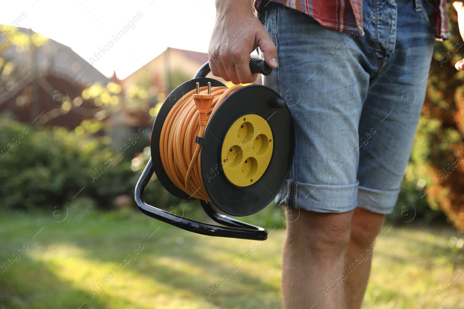 Photo of Man with extension cord reel outdoors on sunny day, closeup