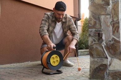 Man with extension cord reel in backyard