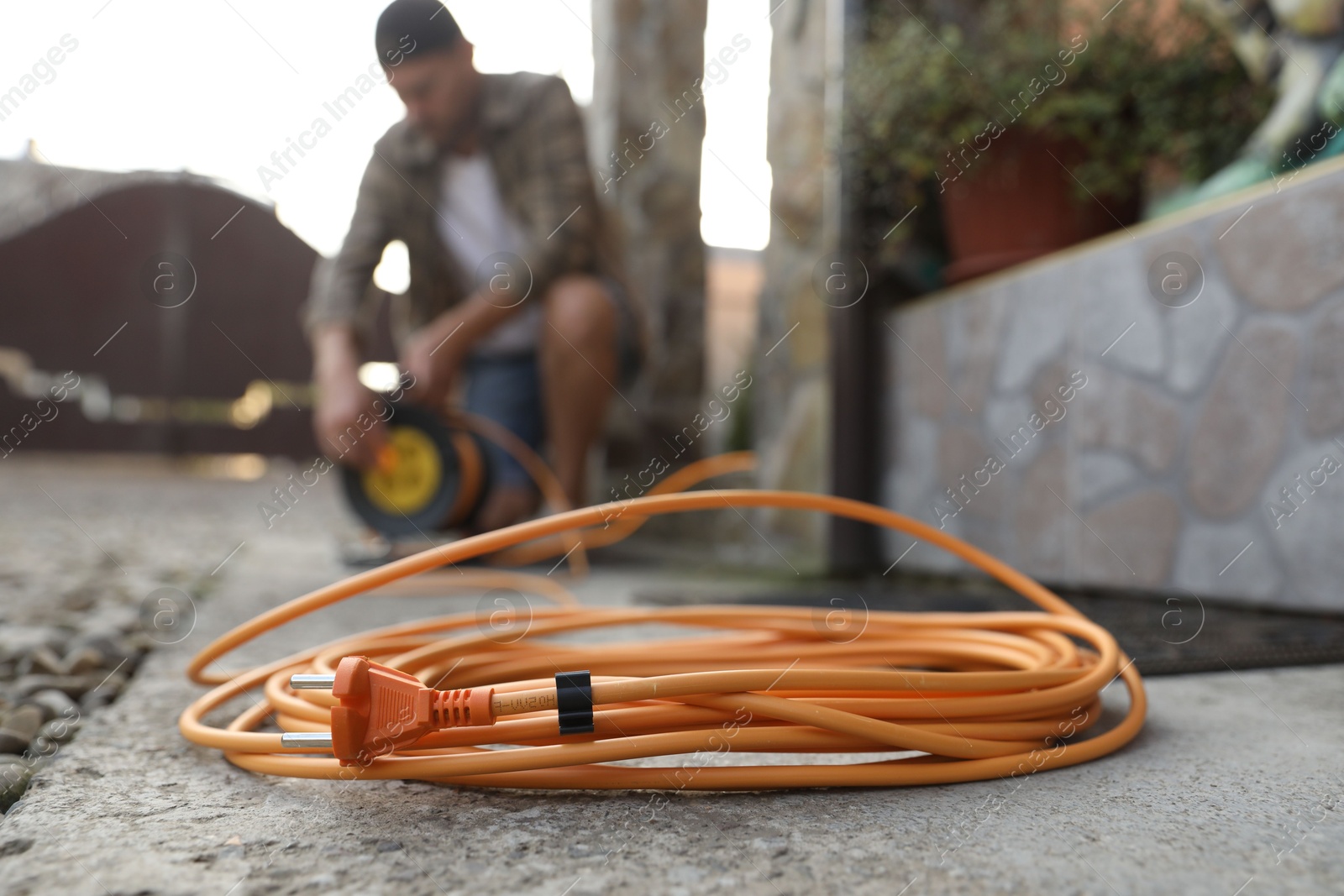 Photo of Man with extension cord reel outdoors, selective focus