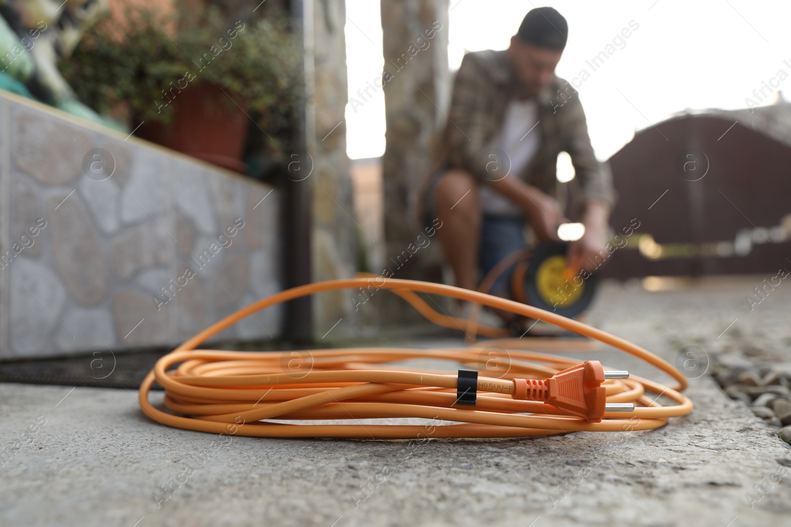 Photo of Man with extension cord reel outdoors, selective focus