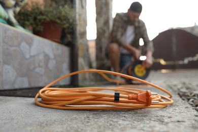 Photo of Man with extension cord reel outdoors, selective focus