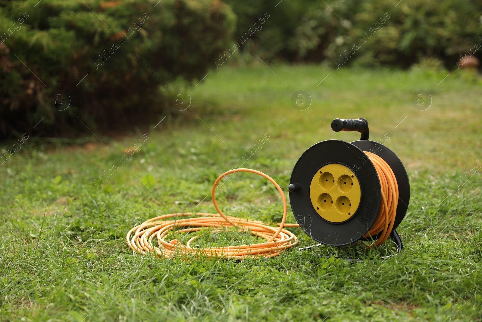 Photo of Extension cord reel on green grass outdoors