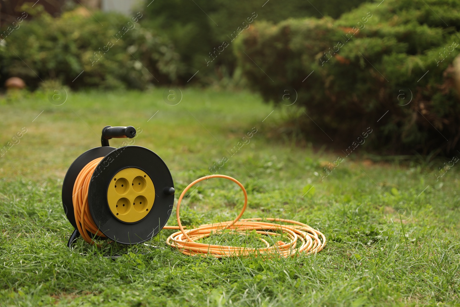 Photo of Extension cord reel on green grass outdoors