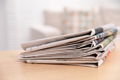 Photo of Stack of newspapers in different languages on table indoors, closeup