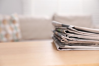 Photo of Stack of newspapers in different languages on table indoors. Space for text