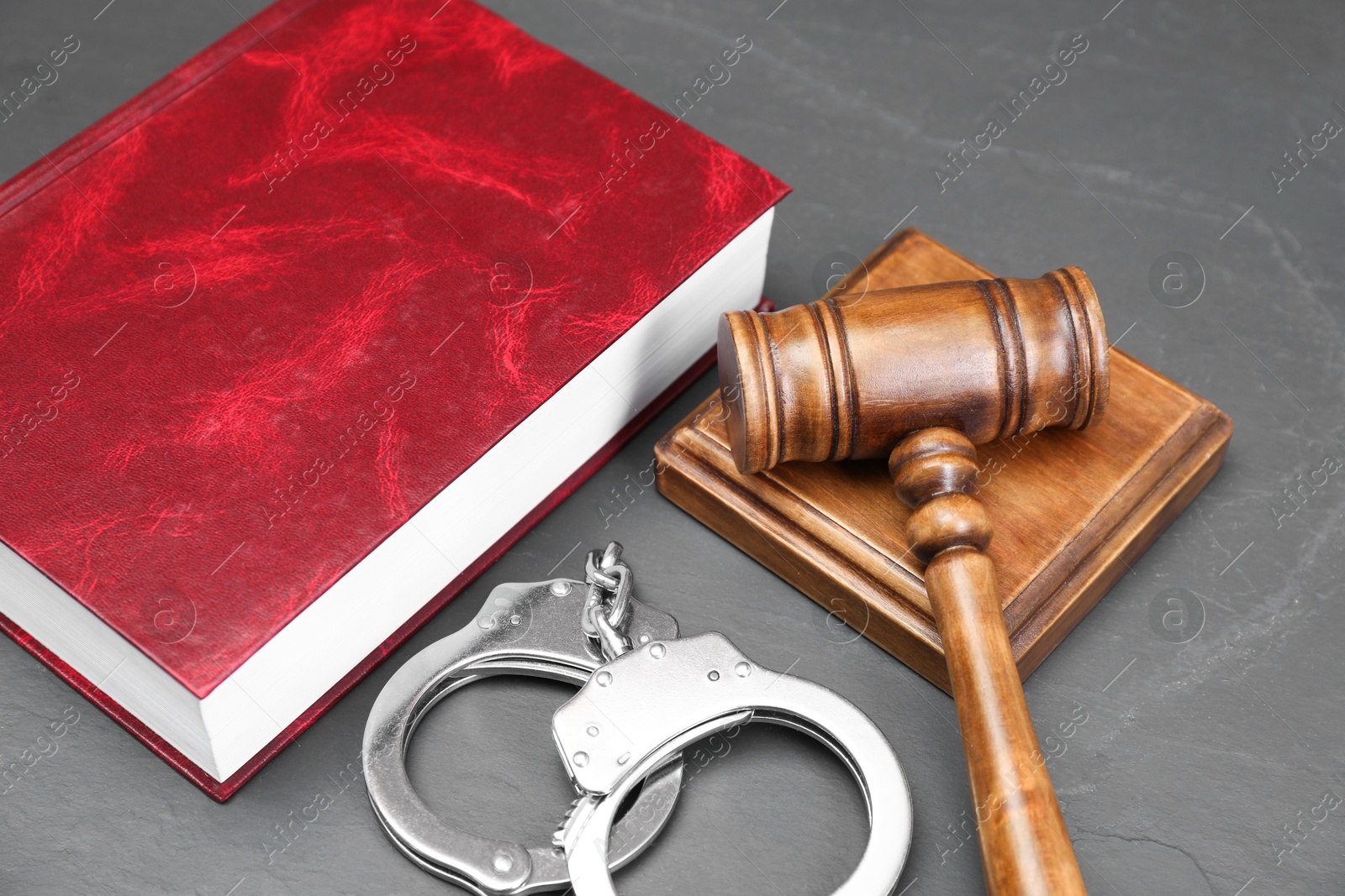 Photo of Book, judge's gavel and handcuffs on gray textured table