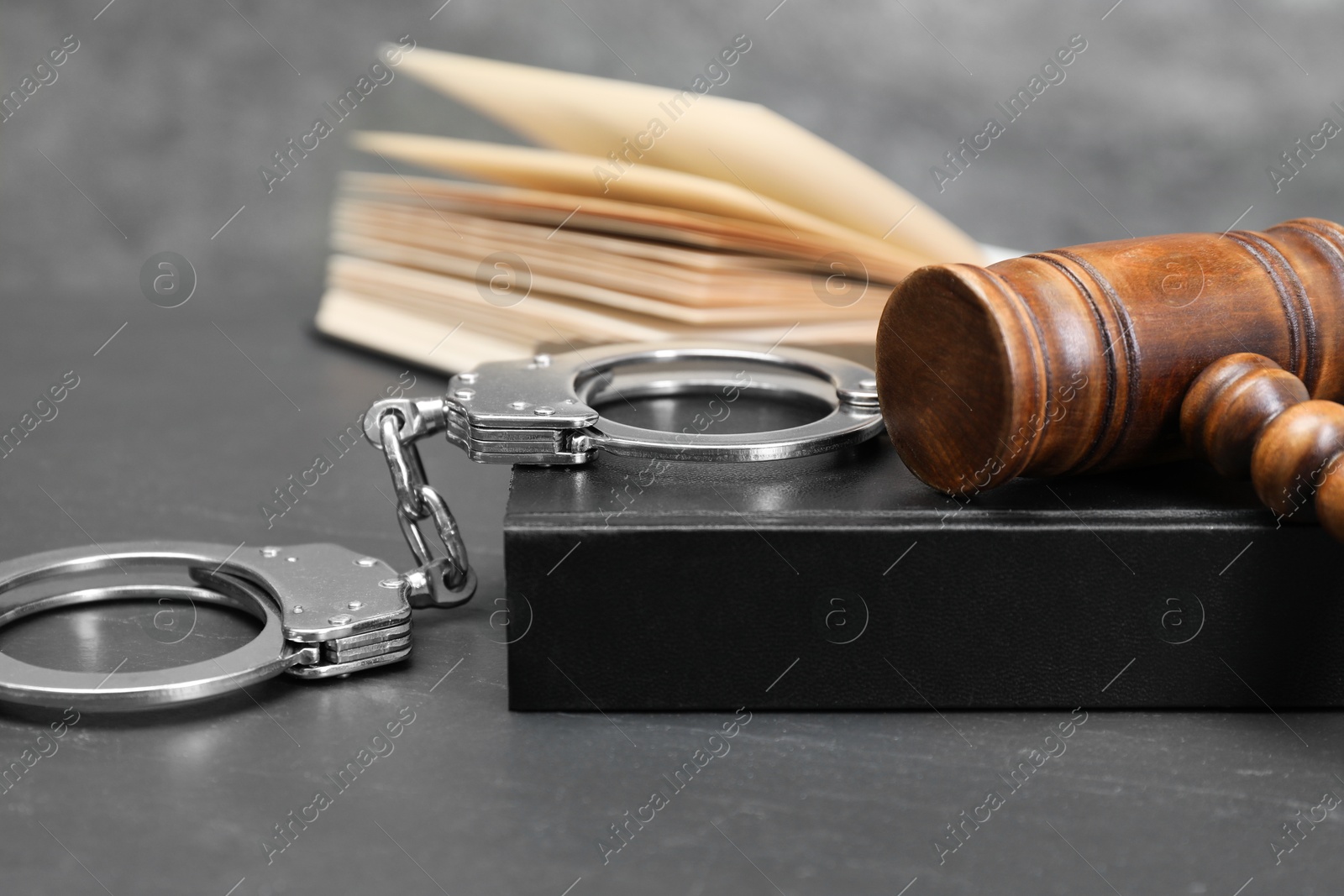 Photo of Books, judge's gavel and handcuffs on gray textured table, closeup