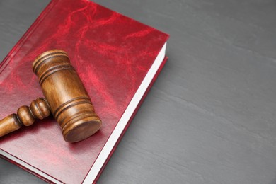 Book and judge's gavel on gray textured table, space for text