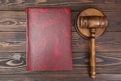 Book and judge's gavel on wooden table, flat lay