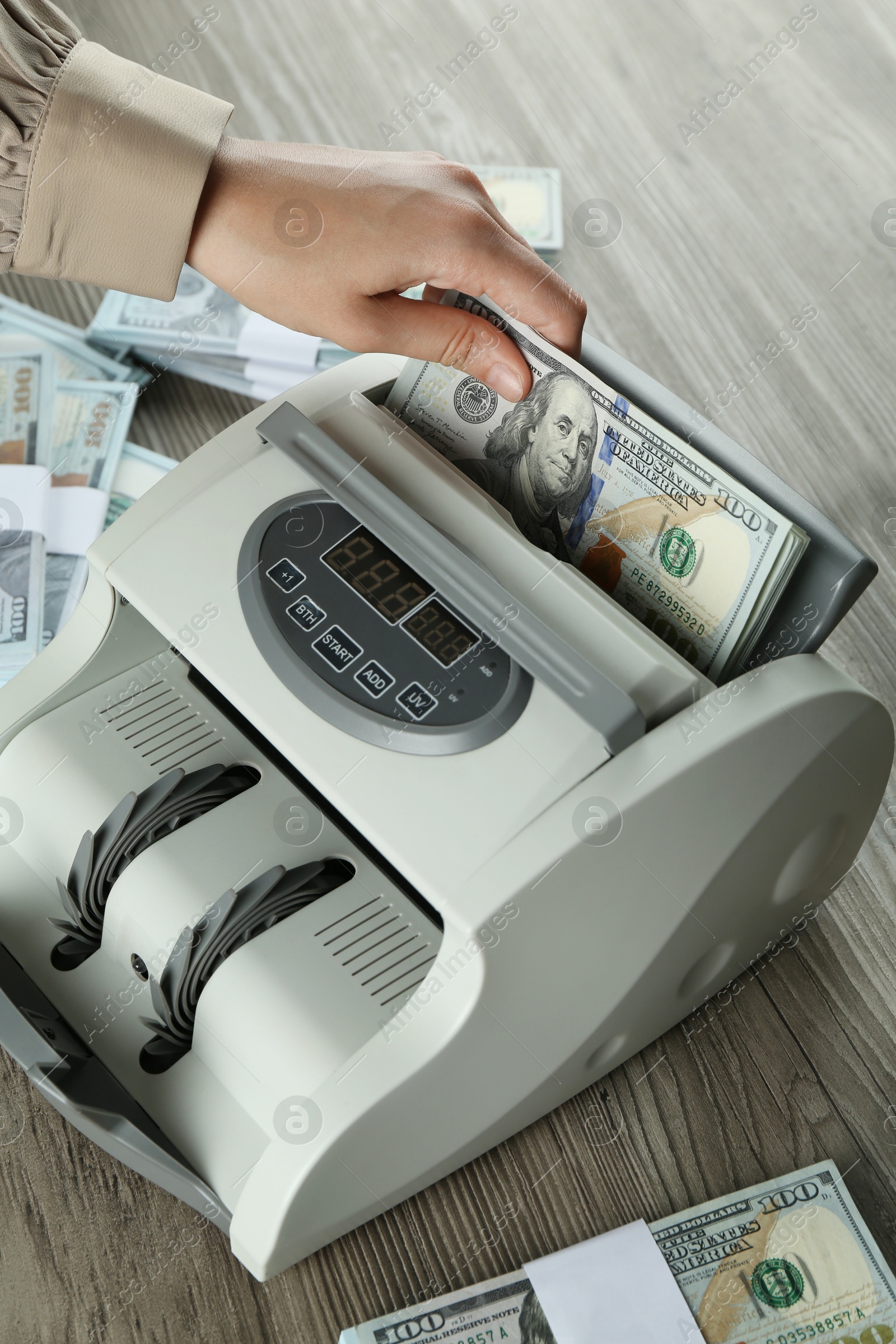 Photo of Woman using money counter machine at wooden table, closeup