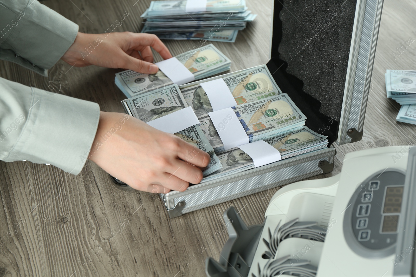 Photo of Woman counting dollar banknotes at wooden table, closeup