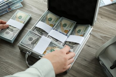 Photo of Woman counting dollar banknotes at wooden table, closeup