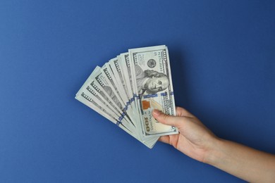 Photo of Woman with dollar banknotes on blue background, closeup