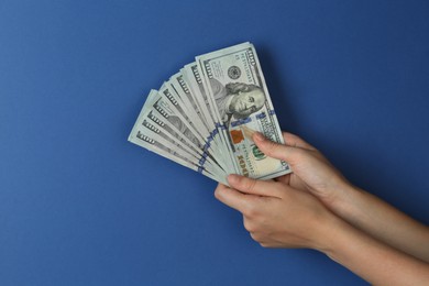 Photo of Woman with dollar banknotes on blue background, closeup