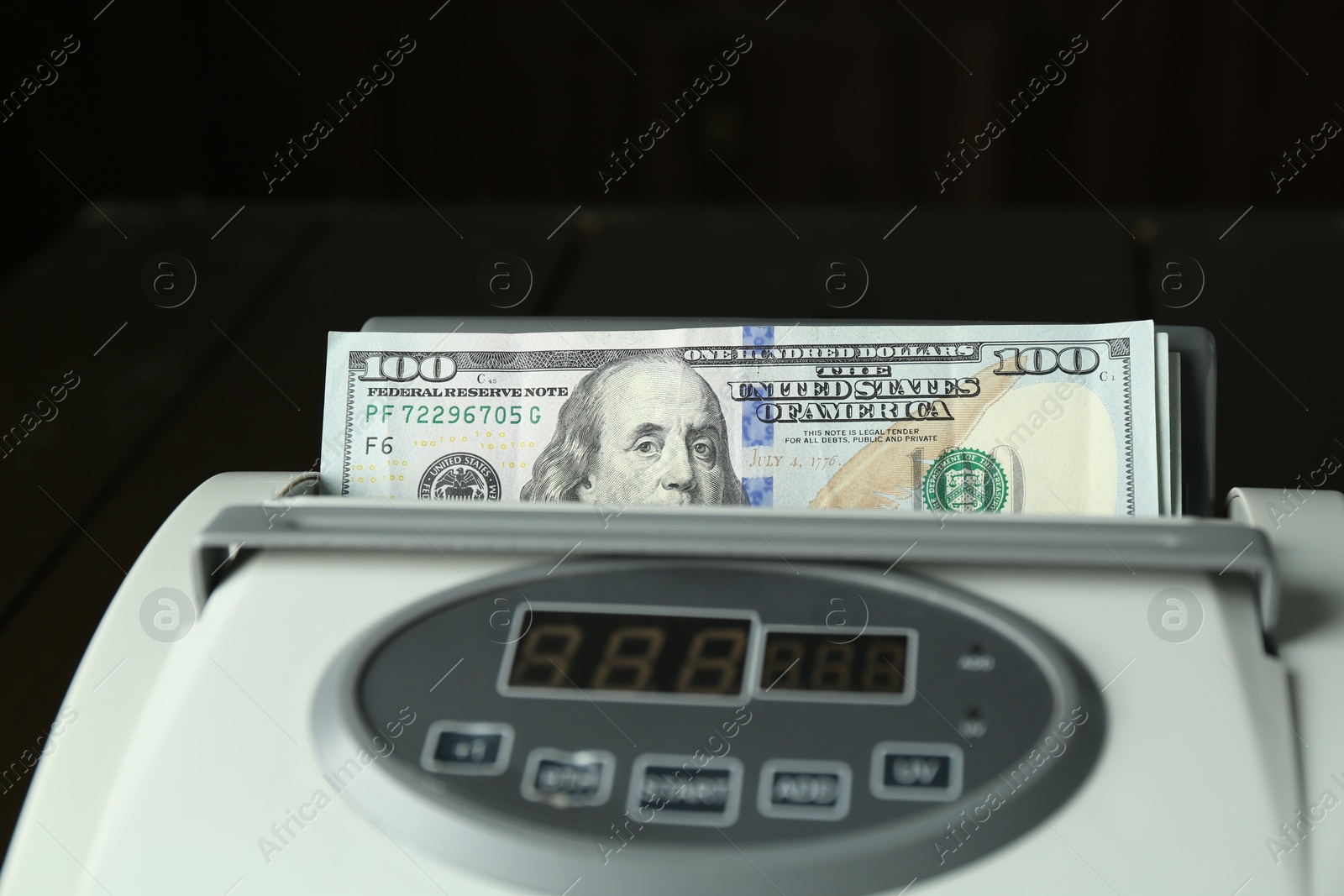 Photo of Money counter machine with dollar banknotes on table, closeup