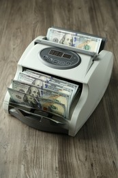 Money counter machine with dollar banknotes on wooden table