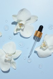 Photo of Beautiful orchid flowers and dropper with cosmetic product in water on light blue background, flat lay