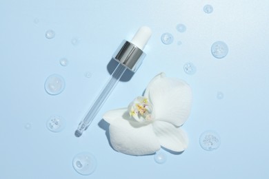 Photo of Beautiful orchid flower and dropper with cosmetic product in water on light blue background, flat lay