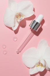 Photo of Beautiful orchid flowers and dropper with cosmetic product in water on pink background, flat lay