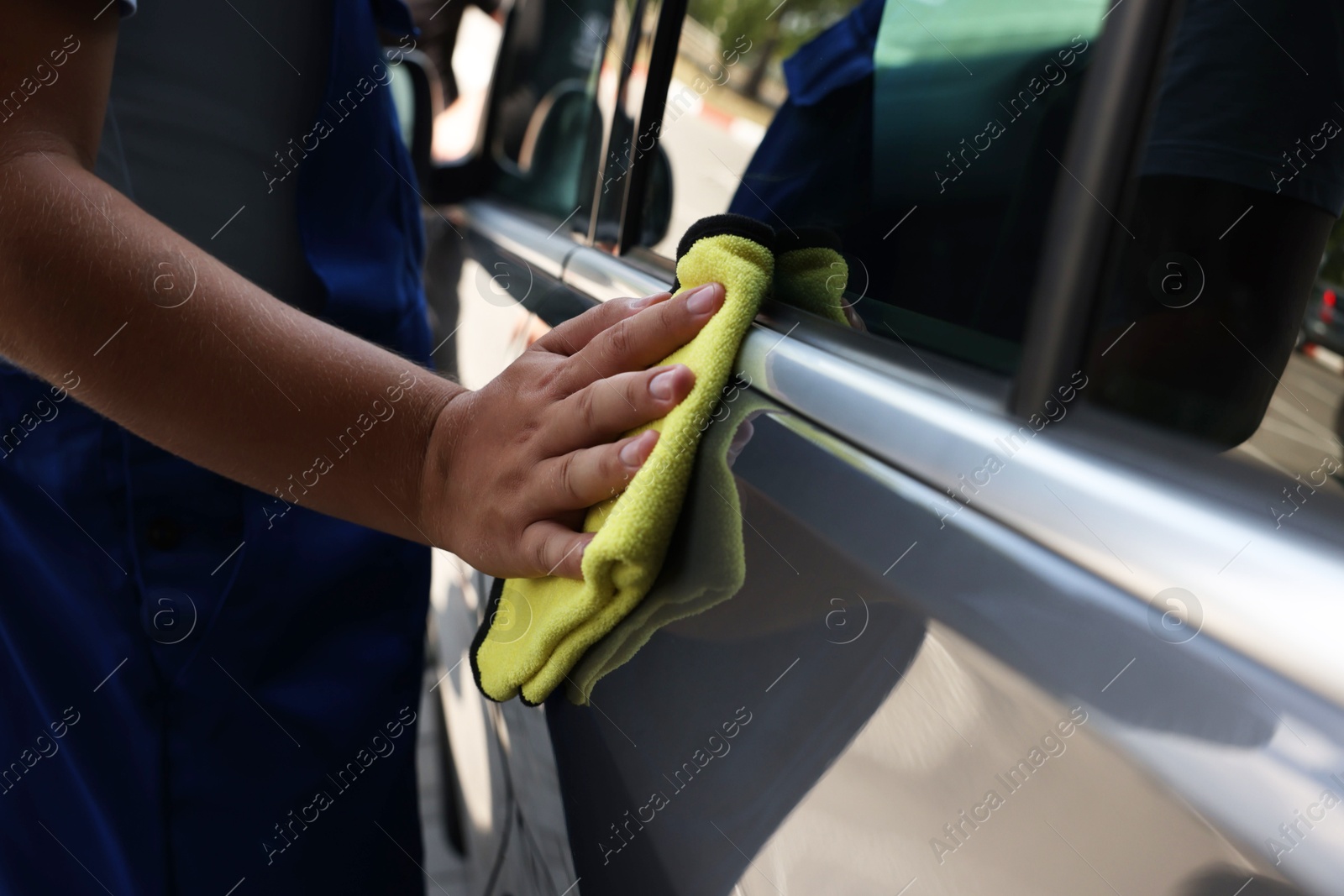 Photo of Man wiping car door with yellow rag, closeup