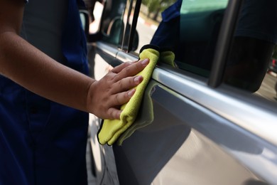 Man wiping car door with yellow rag, closeup