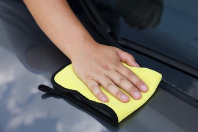 Man wiping car hood with yellow rag, closeup