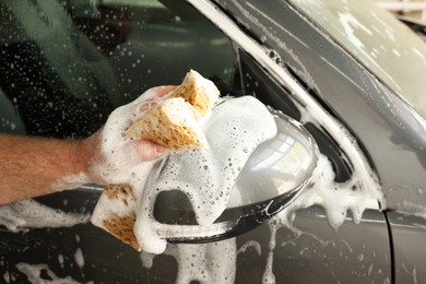 Photo of Man washing auto with sponge at car wash, closeup