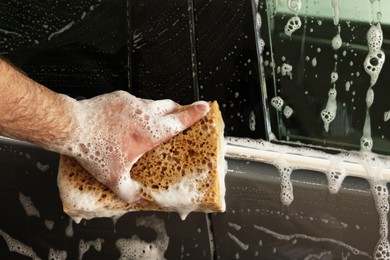 Photo of Man washing auto with sponge at car wash, closeup