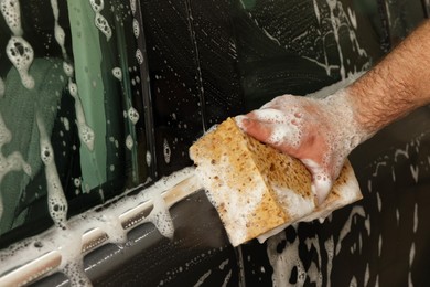 Photo of Man washing auto with sponge at car wash, closeup