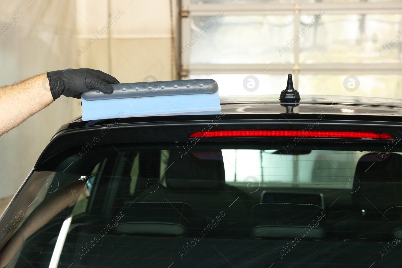 Photo of Man wiping auto with squeegee brush at car wash, closeup