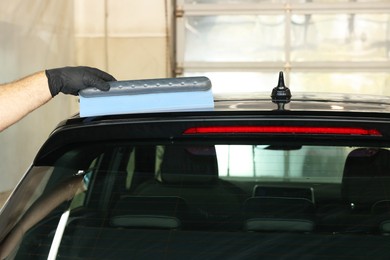 Man wiping auto with squeegee brush at car wash, closeup