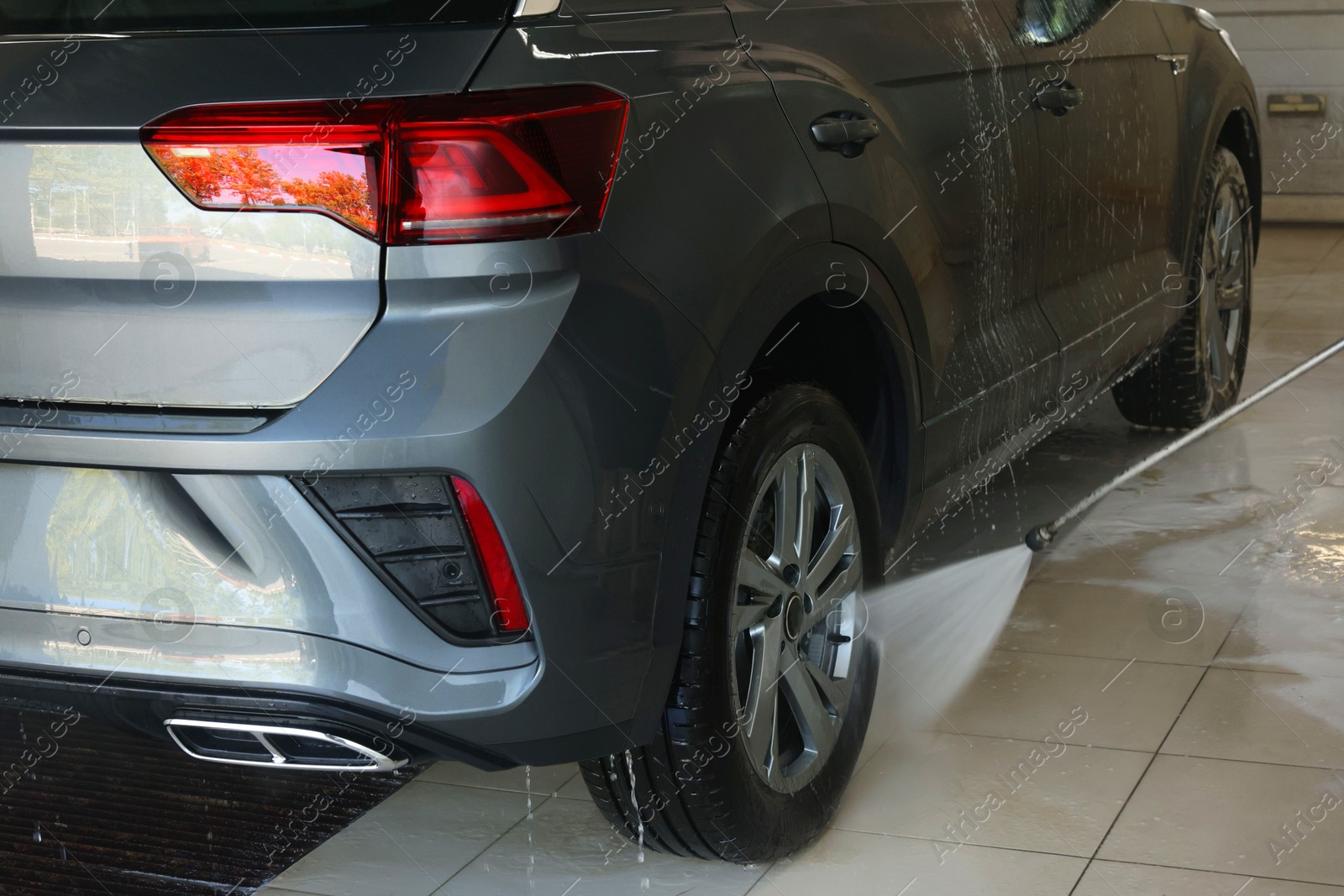 Photo of Washing auto with high pressure water jet at car wash, closeup