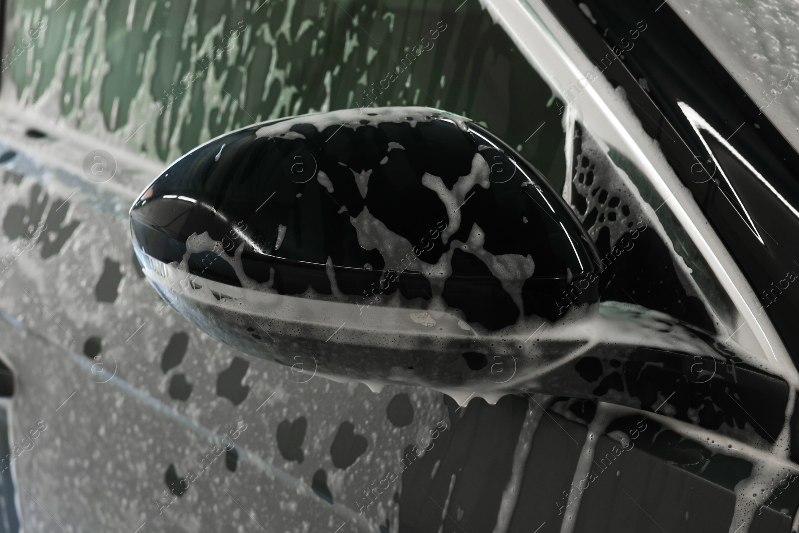 Photo of Auto covered with cleaning foam at car wash, closeup