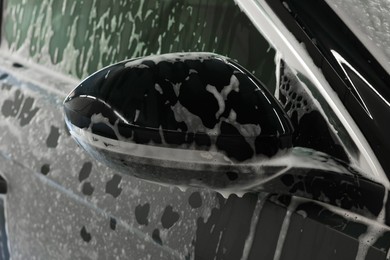 Photo of Auto covered with cleaning foam at car wash, closeup