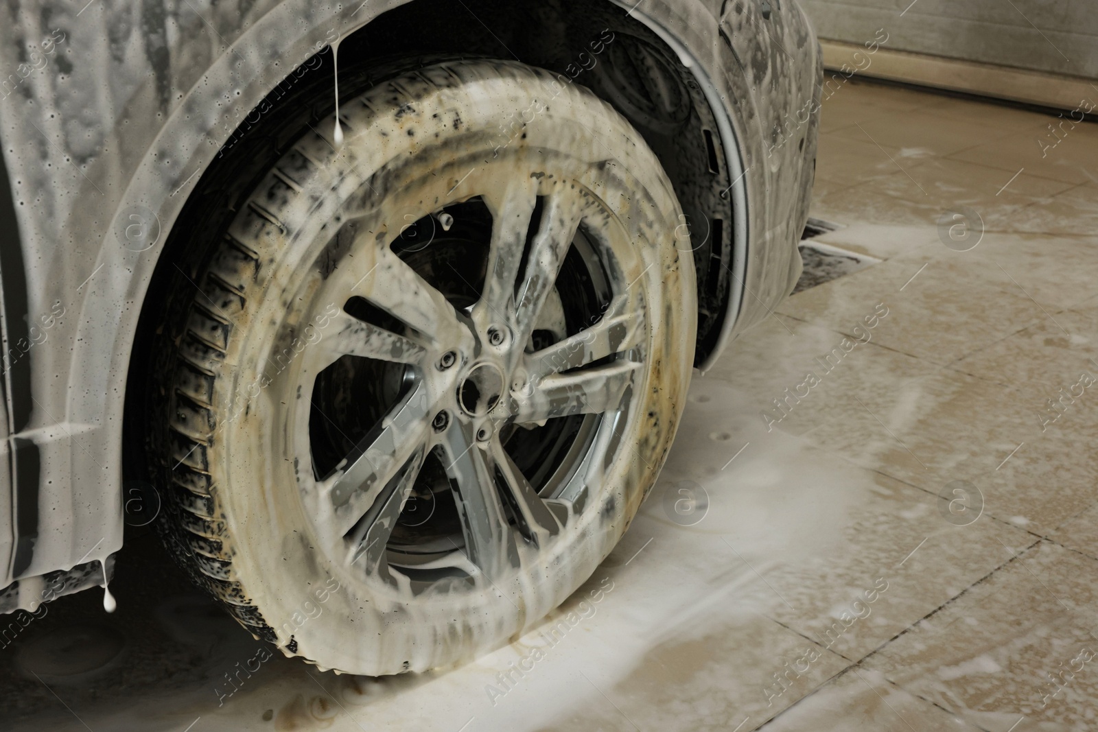 Photo of Auto covered with cleaning foam at car wash, closeup