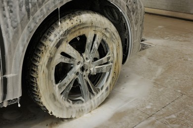 Auto covered with cleaning foam at car wash, closeup