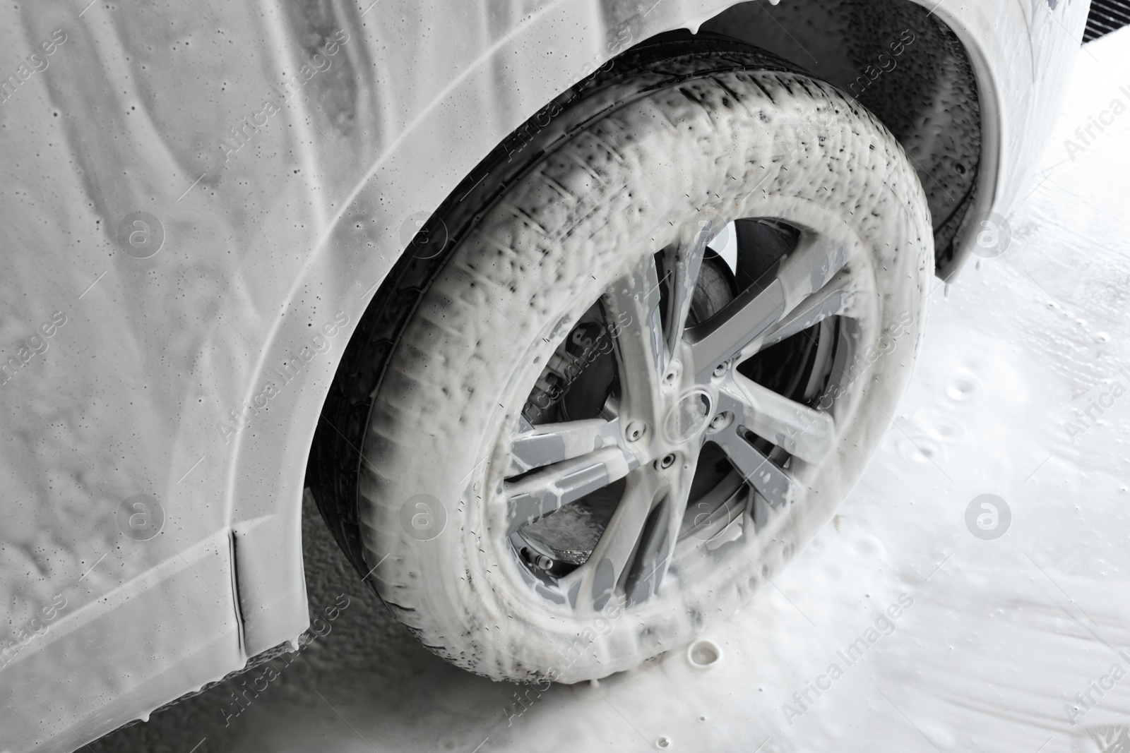 Photo of Auto covered with cleaning foam at car wash, closeup