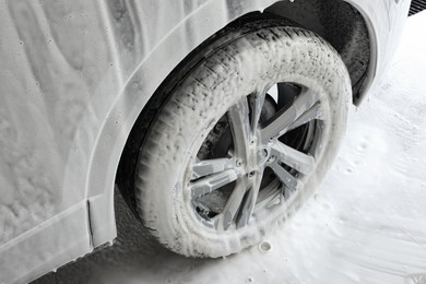 Auto covered with cleaning foam at car wash, closeup